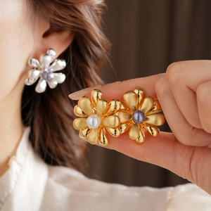 Macro detail of 18k gold plated daisy flower earrings with central pearl inlay