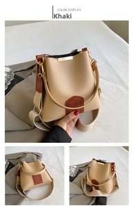 Detail of khaki bucket bag with brown leather trim and wide woven shoulder strap