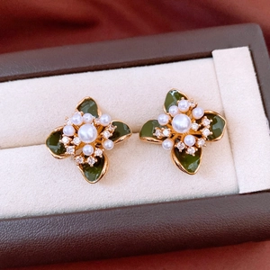 Vue macro de boucles d'oreilles fleur en perles vintage avec pétales verts et or