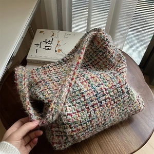 Close-up of colorful knit hobo bag on a wooden table with a warm and cozy home aesthetic