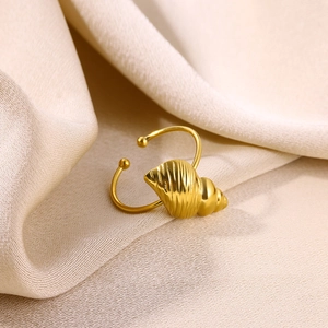 Détail macro d'une bague ouverte en forme de coquillage doré sur du tissu en soie