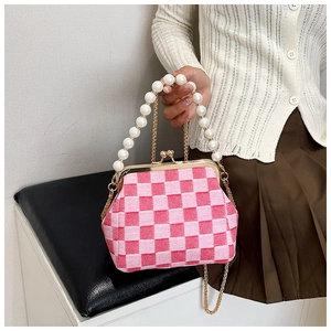 Detail of pink checkerboard clutch featuring a large pearl handle and metal clasp