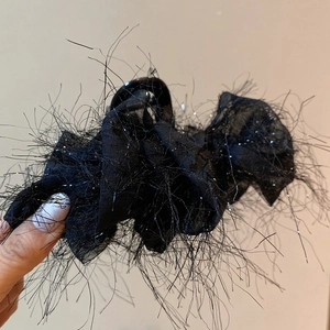 Gros plan sur la pince à cheveux noire à plumes avec résille et paillettes dorées