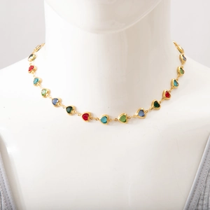 Detailed close-up of gold chain necklace with colorful heart-shaped gems on a mannequin