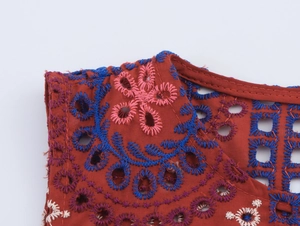 Dettaglio del gilet rosso mattone con ricami intricati e motivi a maglia traforata