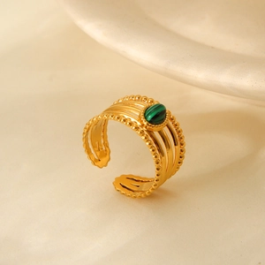 Close-up of gold ring with oval green stone and intricate beaded edge detailing