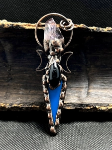 Macro shot of bronze moon pendant featuring amethyst raw stone and black agate inlay
