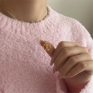 Minimalist gold heart pretzel pendant necklace worn with a pink textured sweater