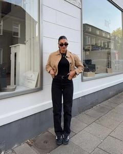 Détail d'une veste courte en daim kaki avec jean noir et baskets au style urbain chic