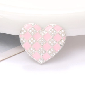 Macro detail of heart-shaped zinc alloy charm with pink enamel checkerboard and pearls