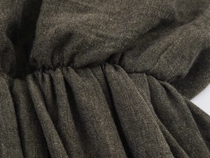 Detail of dark brown cotton linen dress showing premium woven texture and pleating