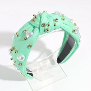 Close-up of mint green knotted headband with heart pearls and sparkling rhinestones