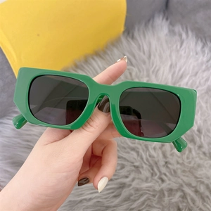 Close-up of bright green rectangular sunglasses with dark grey lenses in hand