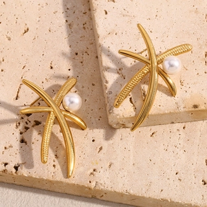 Macro shot of 18K gold plated palm tree pearl earrings on a minimalist stone texture