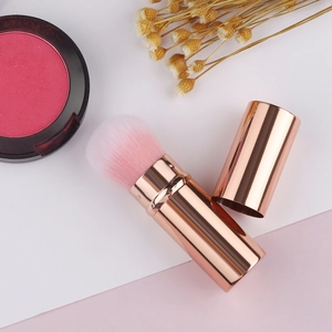 Retractable rose gold makeup brush with soft pink gradient bristles and metal cap