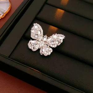 Close-up of a silver butterfly brooch with sparkling zircon stones on black velvet