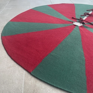 Detailed knit texture of red and green striped Christmas tree skirt with secure ties