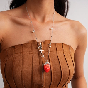 Close-up of strawberry pendant necklace with white pearls and tiny cross star charm