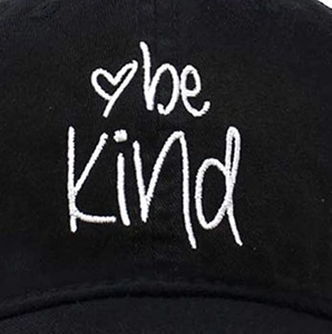 Close-up of be Kind white embroidery and heart symbol on black cotton baseball cap