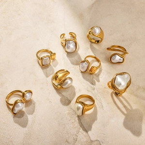 Macro detail of gold titanium steel rings with irregular pearls on a stone texture