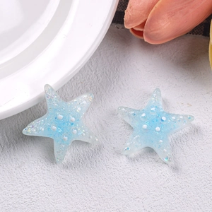 Macro shot of two blue glitter resin starfish charms for DIY hair clips and crafts