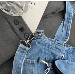 Detail of blue denim tote bag showing silver metal buckles and brown stitching work