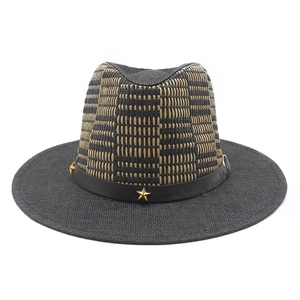 Woven straw cowboy hat with black decorative band and golden star studs on white background