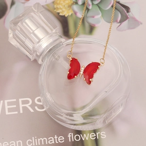 Elegant gold chain necklace with a faceted red butterfly pendant and zircon accents