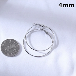 Macro view of 4mm thick silver hoop earrings shown next to a coin for scale reference