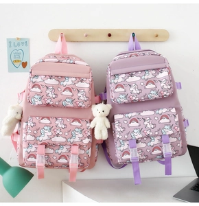 Pink and purple nylon unicorn backpacks with cute plush bear charms hanging on hooks