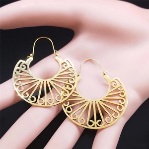 Detail of bohemian gold fan-shaped hollow carved stainless steel earrings on black background