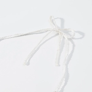 Détail d'un nœud en cordon blanc tissé sur une robe de plage en crochet rayée