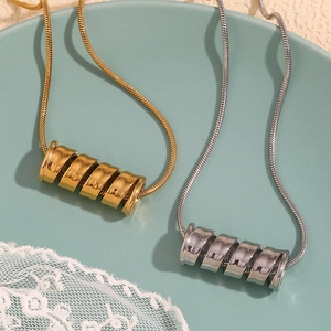 Detailed shot of gold and silver spiral spring pendants on fine snake chains in a dish