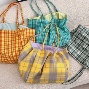 Vue de dessus de quatre sacs cabas en toile à carreaux jaunes, violets, oranges et verts