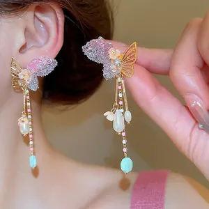 Pink butterfly tassel earrings with sparkling rhinestones and white pearls on a model