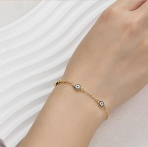 Detailed view of gold evil eye bracelet with blue zircon stones on a model wrist