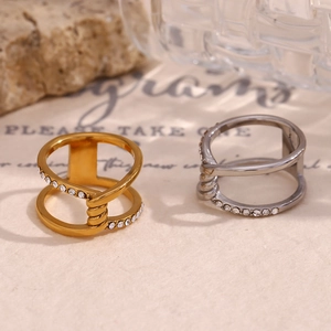 Detail von zweilagigen Kreuzringen in Gold und Silber mit Mikropavé-Kristallen