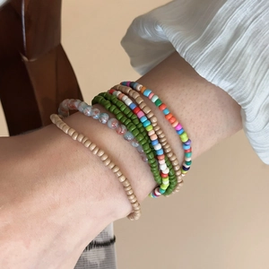 Detailed view of layered bohemian beaded bracelets in green and marble tones on wrist