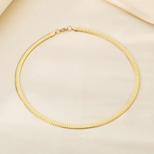 Detailed view of golden herringbone snake chain necklace with lobster clasp on beige satin