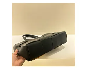 Detailed bottom view of large black woven leather tote bag with wide weave texture