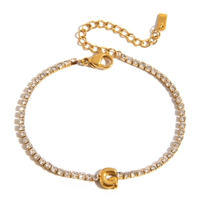 Macro detail of 18K gold letter G charm on tennis bracelet with shimmering cubic zirconia