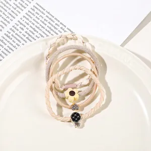 Set of five elastic hair bands with flower and heart charms on a white ceramic plate
