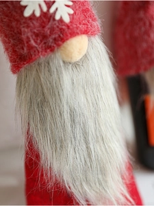 Macro shot of plush Christmas gnome with red knitted hat and long grey faux fur beard