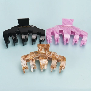 Detailed view of large acetate shark hair clips in black, pink, and brown marble finish