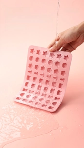 Close-up of pink silicone candy mold being rinsed under water to show easy cleaning