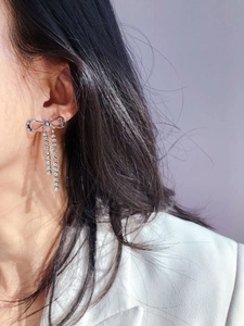 Detail of sparkling crystal bow tassel earrings on model showing elegant silver movement