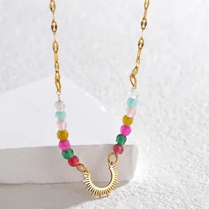 Detailed shot of golden beaded necklace with colorful stones and sun pendant