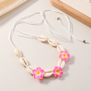 Détail du collier bohème avec des coquillages blancs et des fleurs de frangipanier