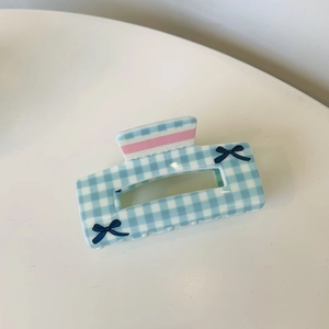 Close-up of blue and white checkered hair claw clip with pink stripes and blue bows