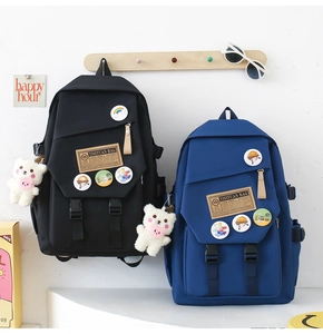 Detail of nylon backpacks in black and blue featuring cute bear plush charms and badges